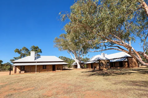 Stone heritage buildings and eucalyptus trees at Alice Springs Telegraph Station
