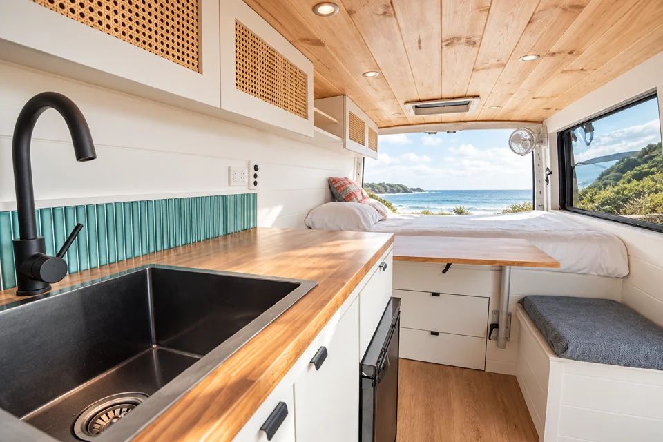 A compact campervan interior with its kitchen and rear sleeping area