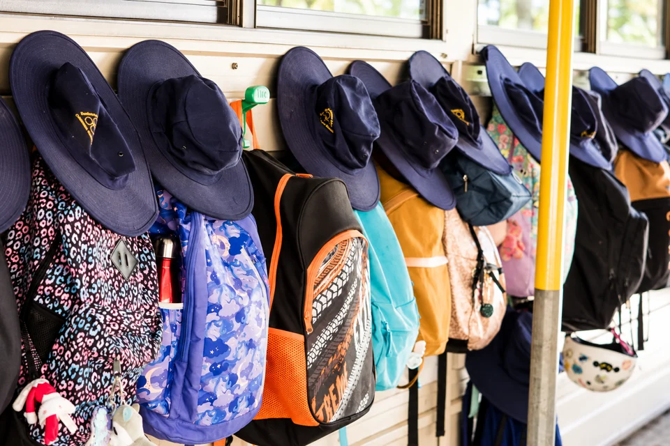 School bags and broad-brimmed hats hanging on hooks