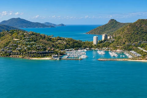 Boats inside Hamilton Island’s two breakwaters below the wooded village and hills