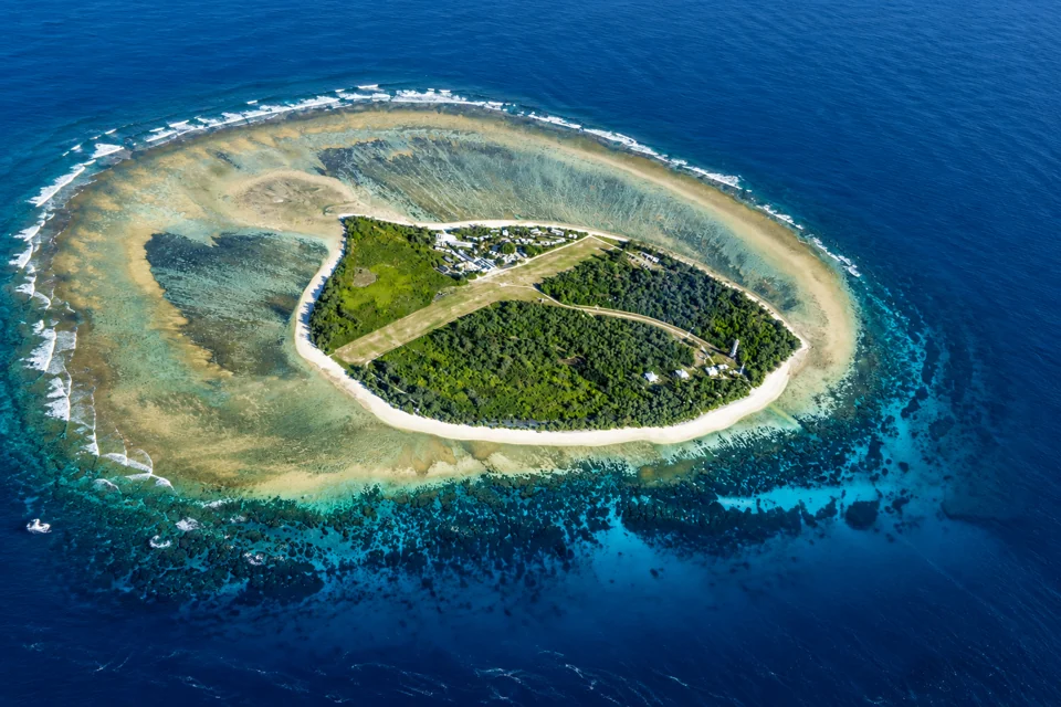Aerial view of Lady Elliot Island showing the single grass runway, low resort buildings and shallow reef